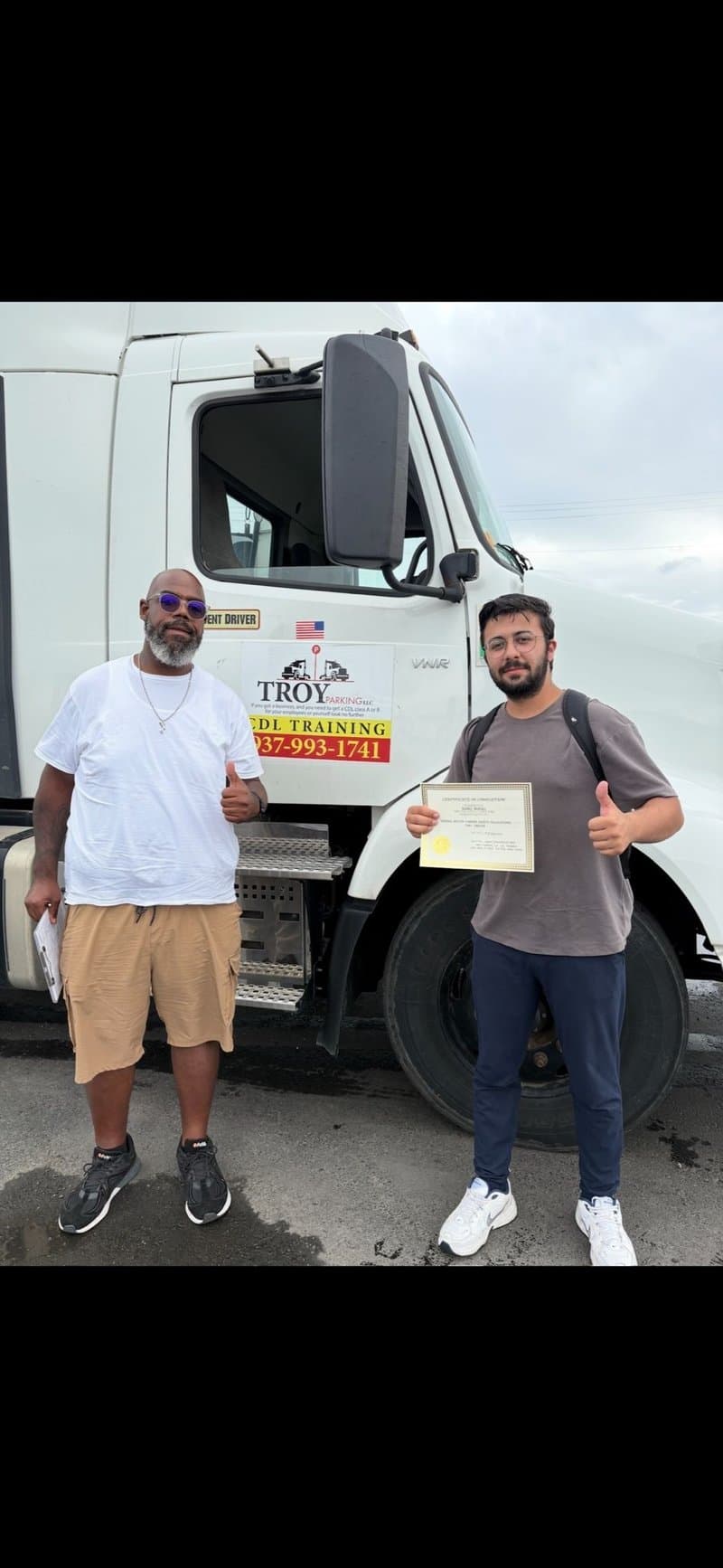 Graduate holding CDL certificate next to Troy CDL truck